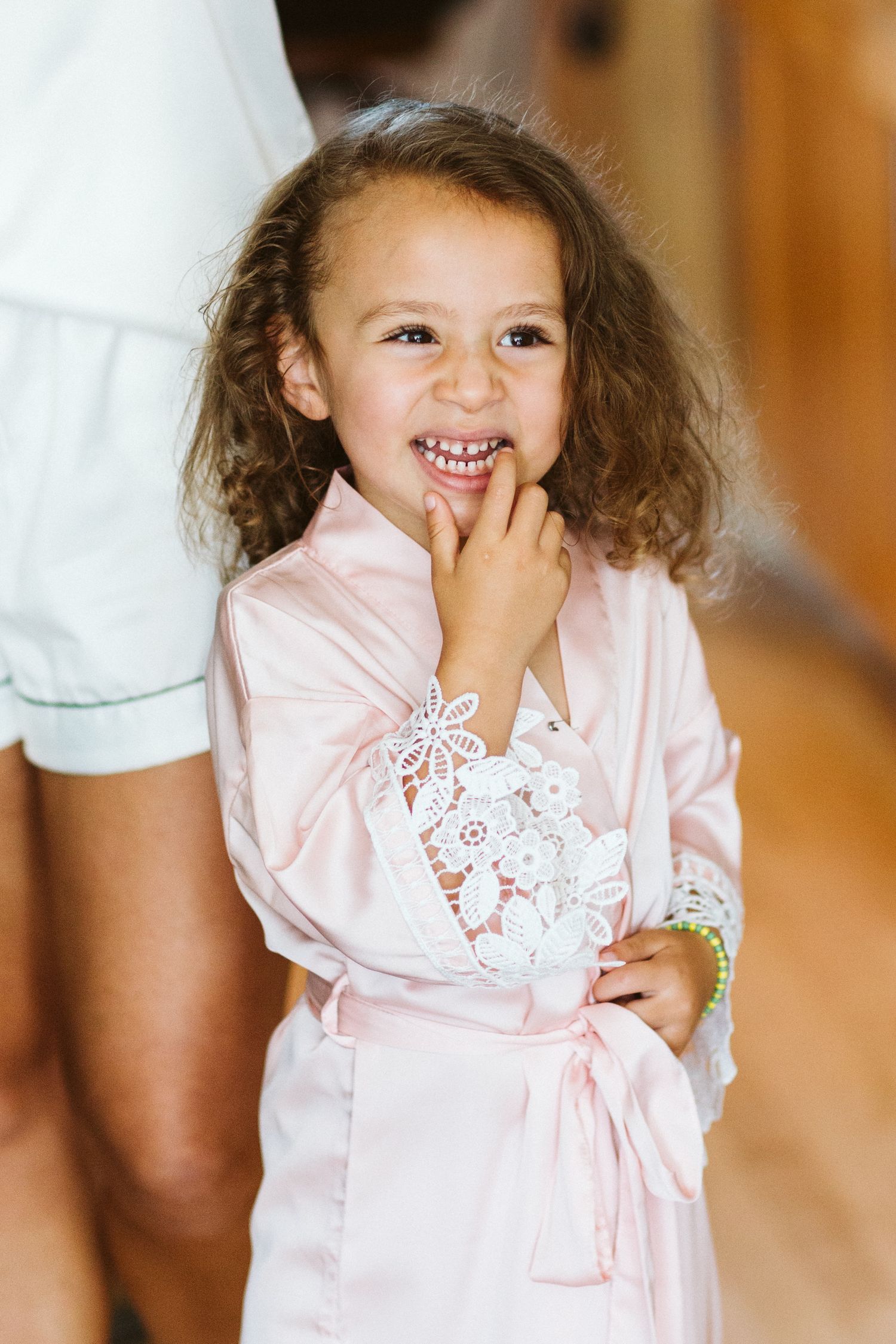 Young child wearing pink silk robe with lace details.