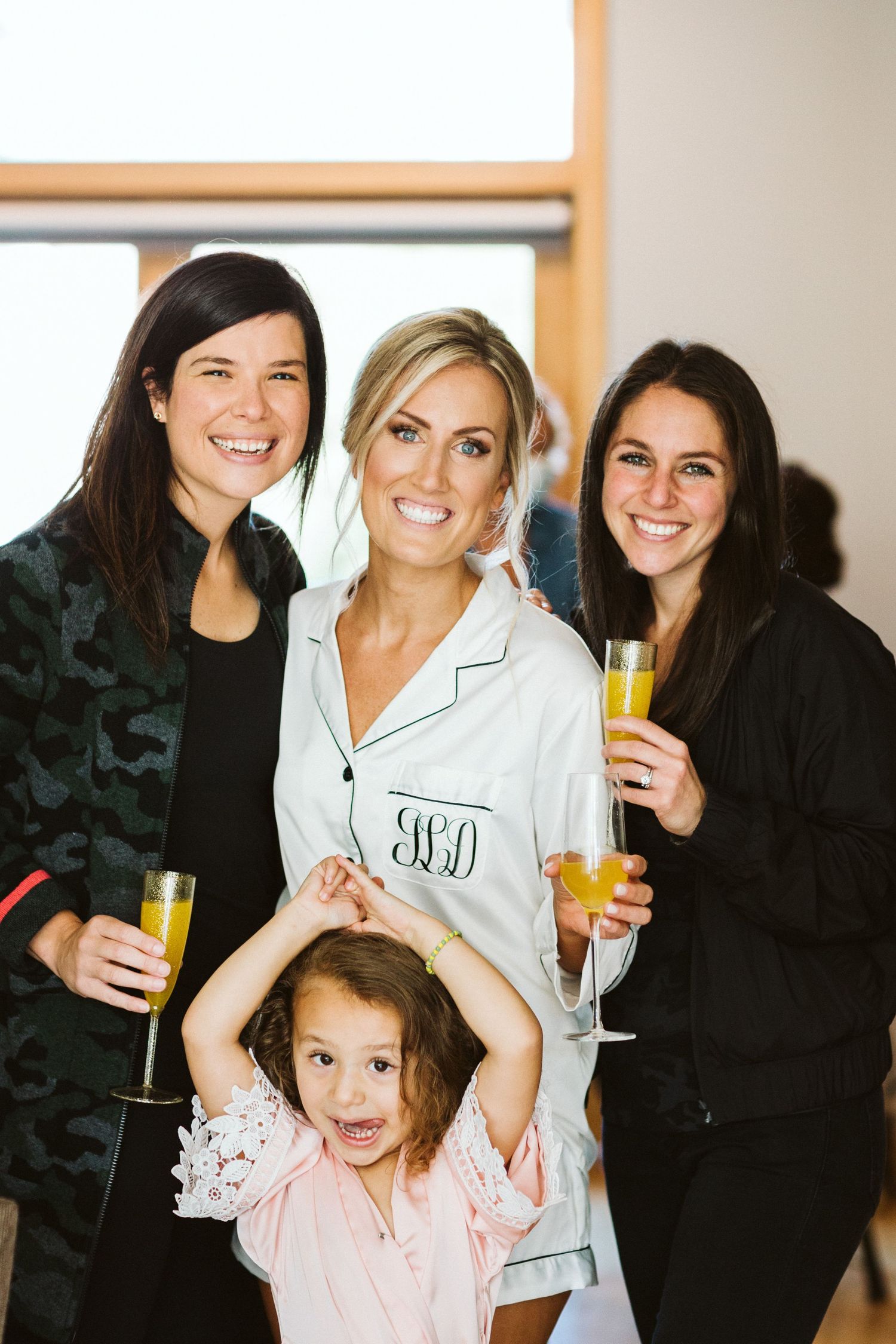 Group wearing matching robes celebrating with champagne in bright indoor setting.