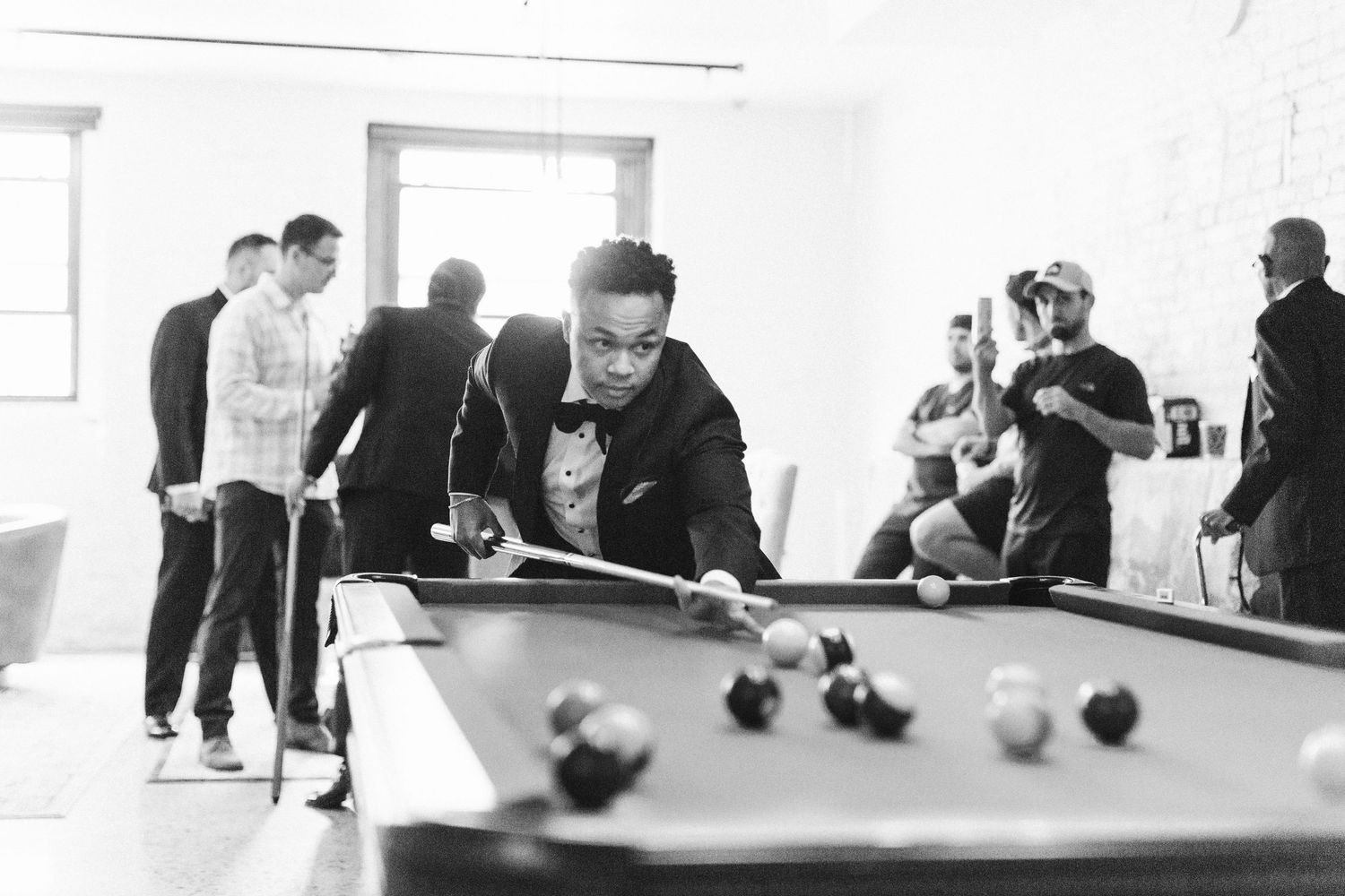 Wide shot of people playing billiards in a modern industrial space.
