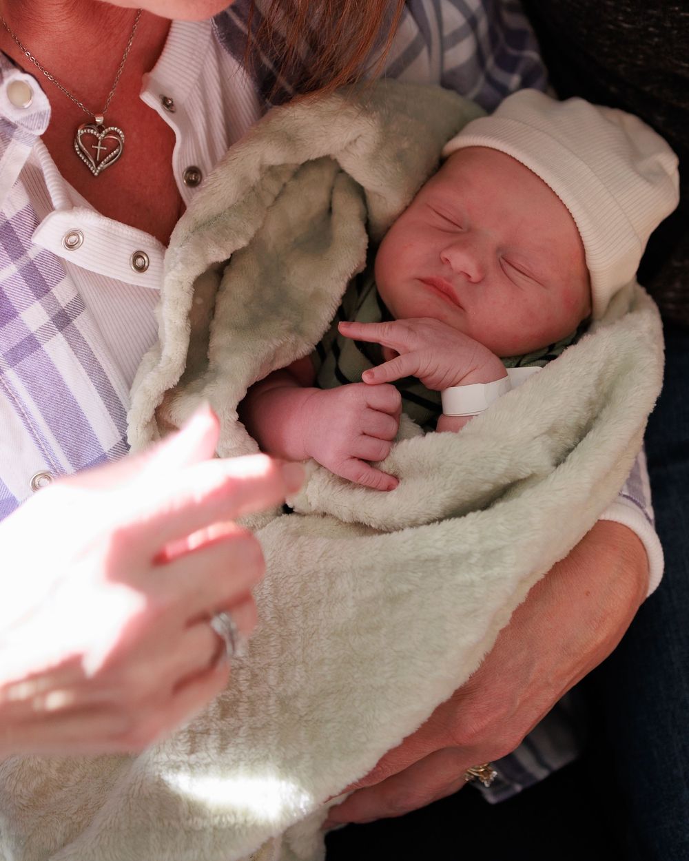 Sleeping newborn wrapped in cream blanket with sunlight streaming across.
