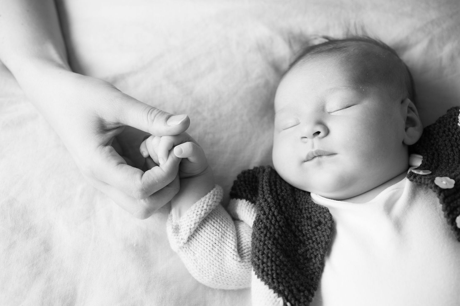 A black and white photo of a peacefully sleeping baby, captured in a cozy home setting in Buckinghamshire by Abigail's Studio.