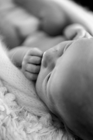 Black and white close-up of a sleeping baby's delicate features on textured fabric.