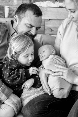 A tender family moment captured in black and white as they cuddle together with a newborn.