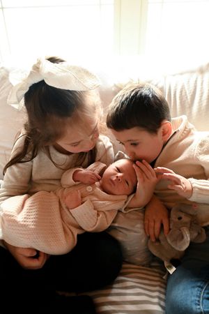Sunlit series of intimate family moments with newborn on light colored couch.
