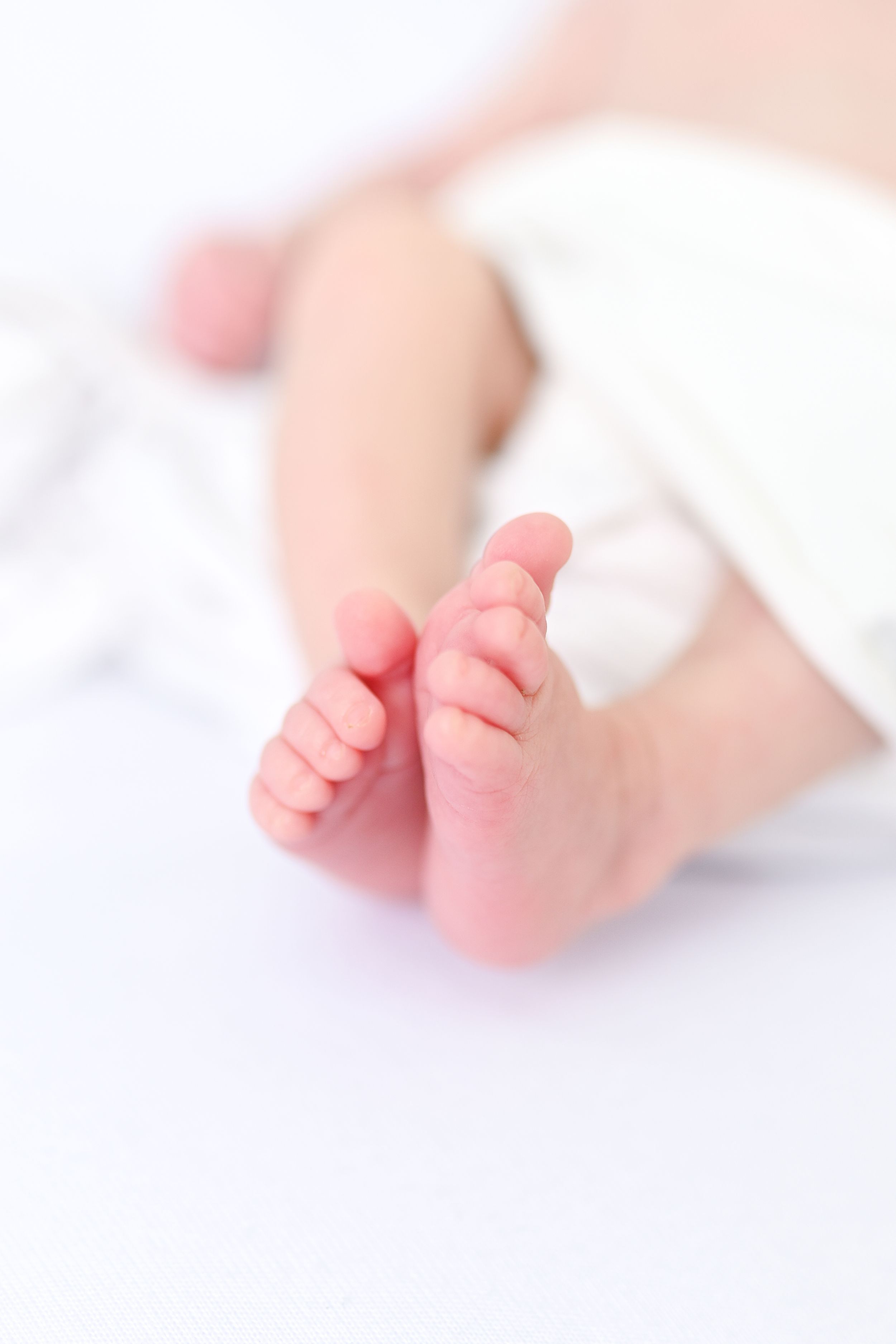 Delicate close-up photographs of baby feet against soft white background.