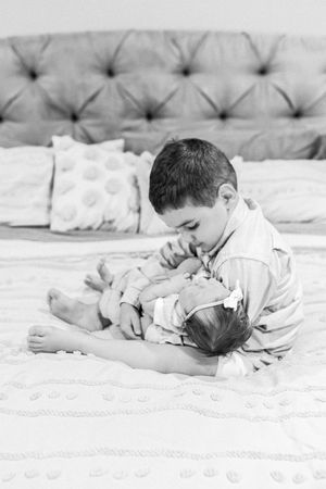 Black and white series of newborn resting on tufted cushion surface.