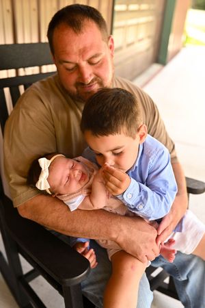 Sequence showing tender moments between adult and infant on wooden chair.