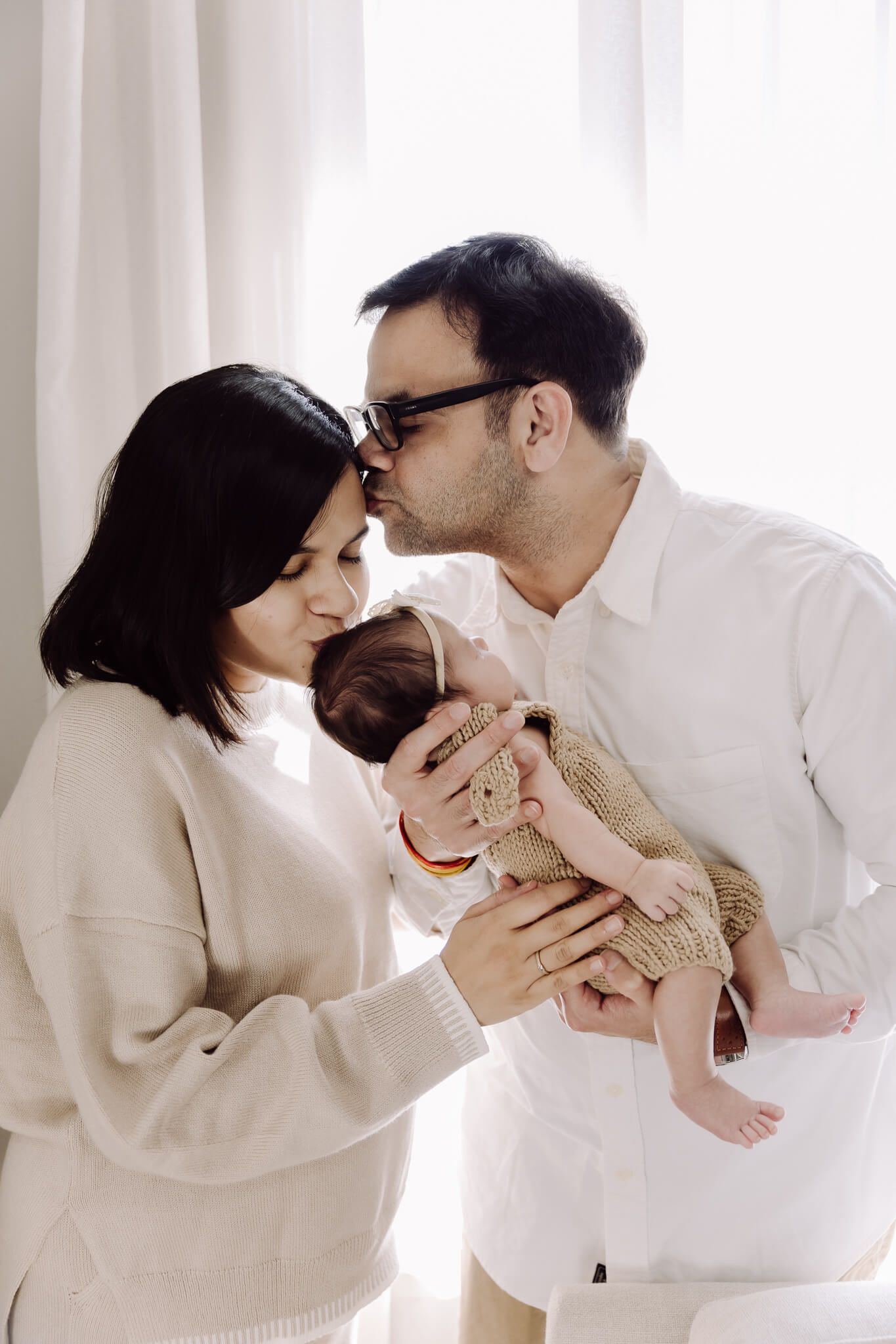 Bay Area lifestyle newborn session with parents snuggling baby in natural light.
