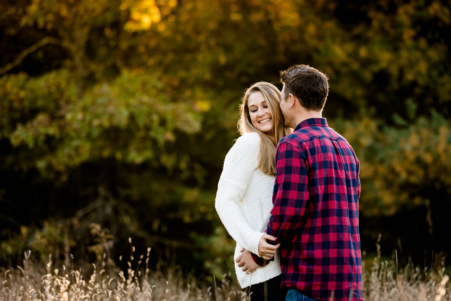 Couple sharing romantic moment in autumn forest with golden sunlight.