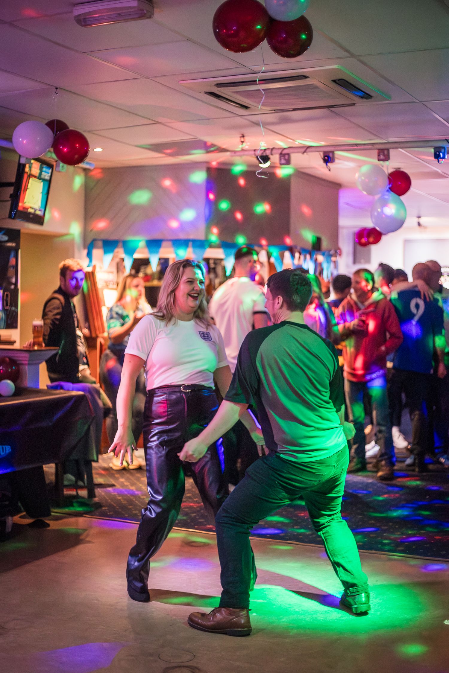 Man and woman dancing happily with each other at a disco in a sports club bar.