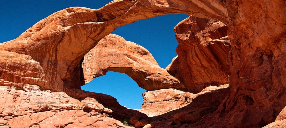 Double O Arch, a striking natural sandstone formation with two openings carved by erosion, stands tall in the desert landscape.