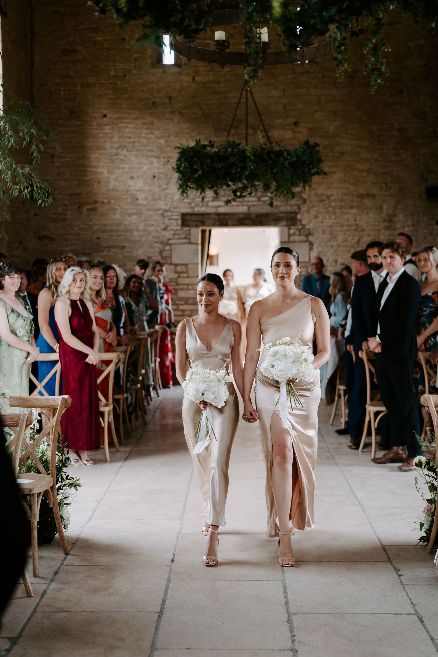 bridesmaids walking down aisle during wedding ceremony at yardspace old gore in cirencester