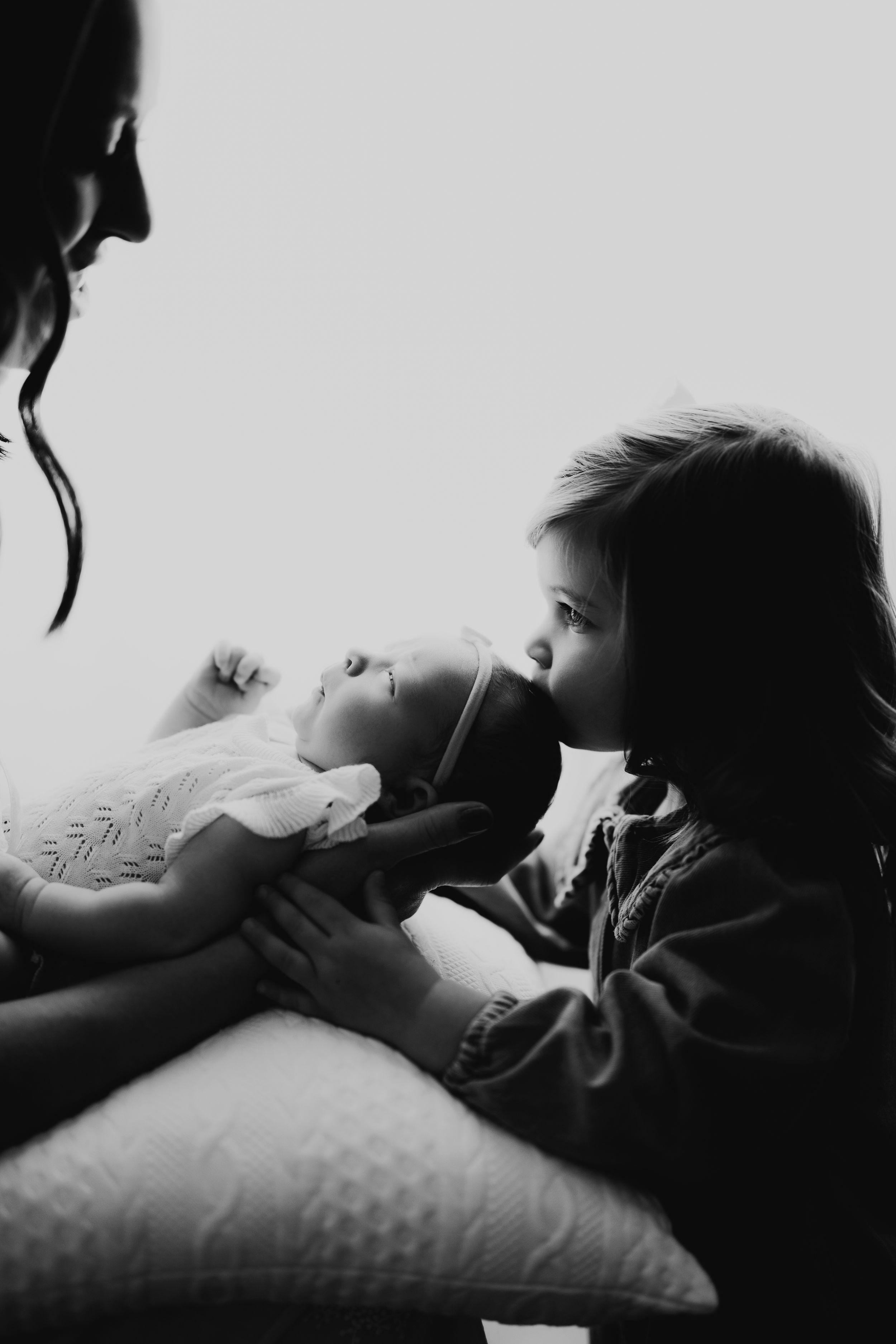 A tender black and white moment shared between a parent and child as they rest together on a cushioned surface.