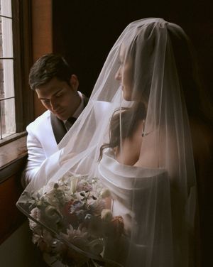 Intimate wedding portrait by window with soft natural light.