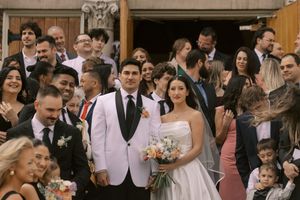 Wedding party poses together outside the church with celebrants in white and black formal attire.