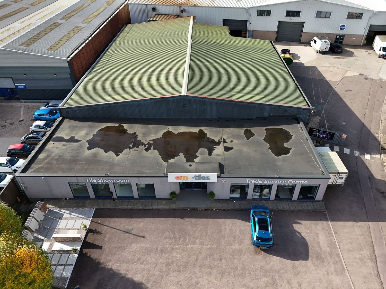 Aerial view of commercial warehouse buildings with white roofs and parking lots in an industrial area.