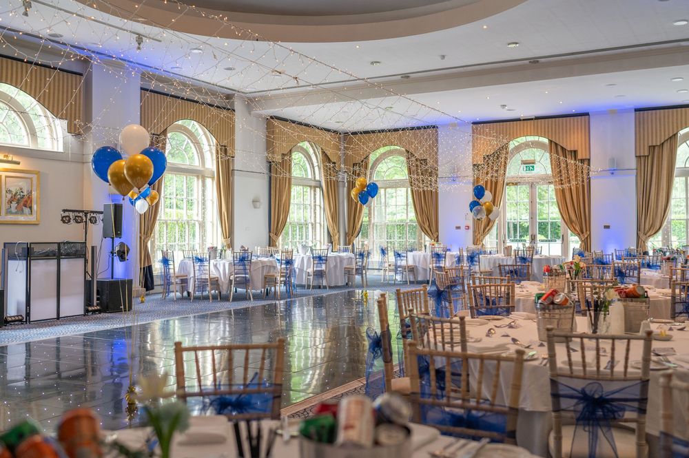 Spacious reception hall decorated with elegant lighting and formal table settings.