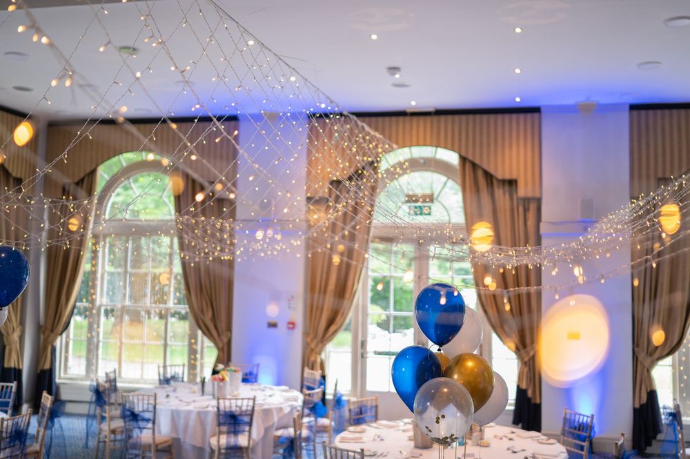 Elegant ballroom with twinkling lights and arched windows set for a formal event.