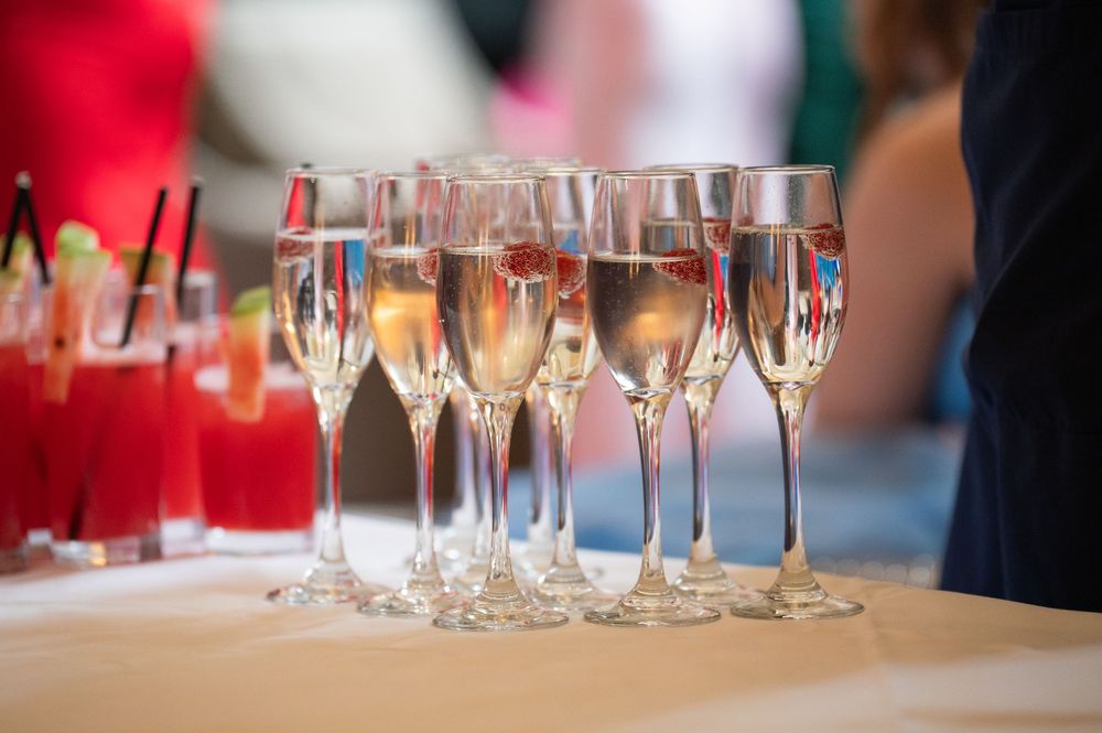 Line of champagne glasses and red cocktails set up for a formal event.