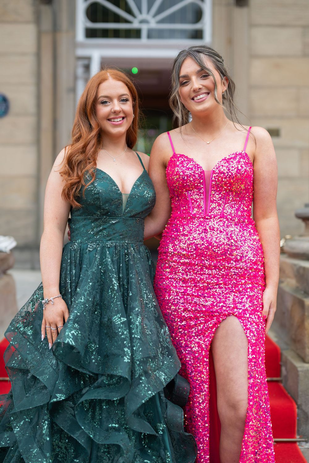 Formal event attendees wearing sparkly emerald and pink evening gowns.