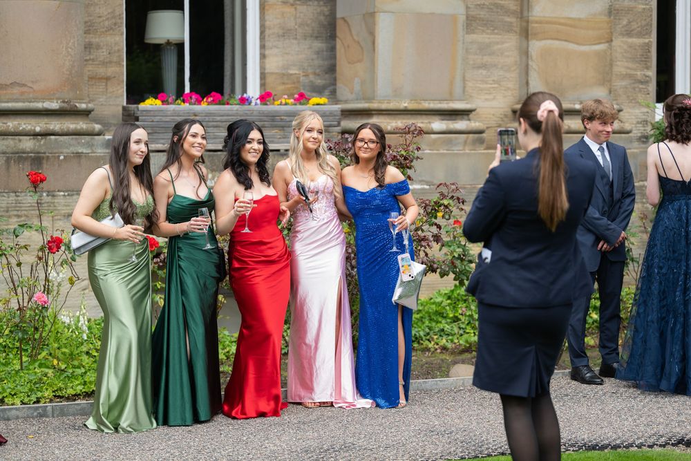 Group photo of event attendees in formal attire outside a stone building.