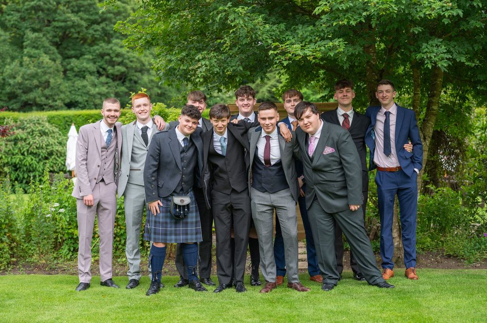 Large group of formally dressed people lined up outdoors for a group photo.