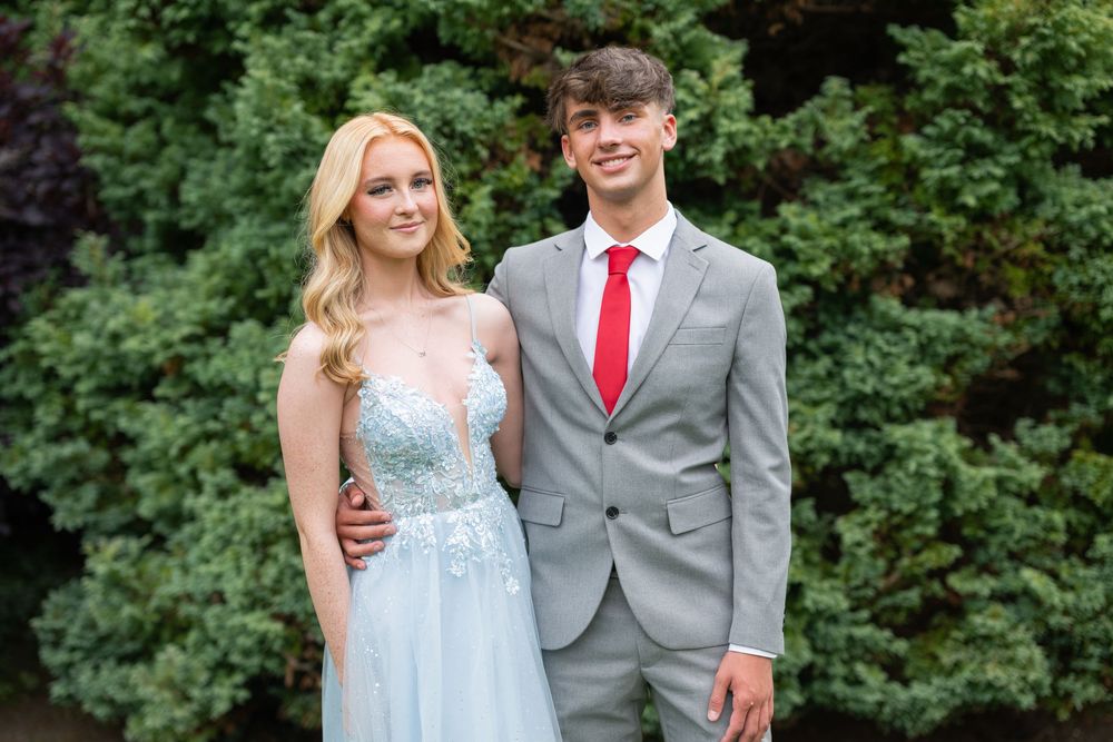 Couples in formal attire pose for photos in an outdoor garden setting.