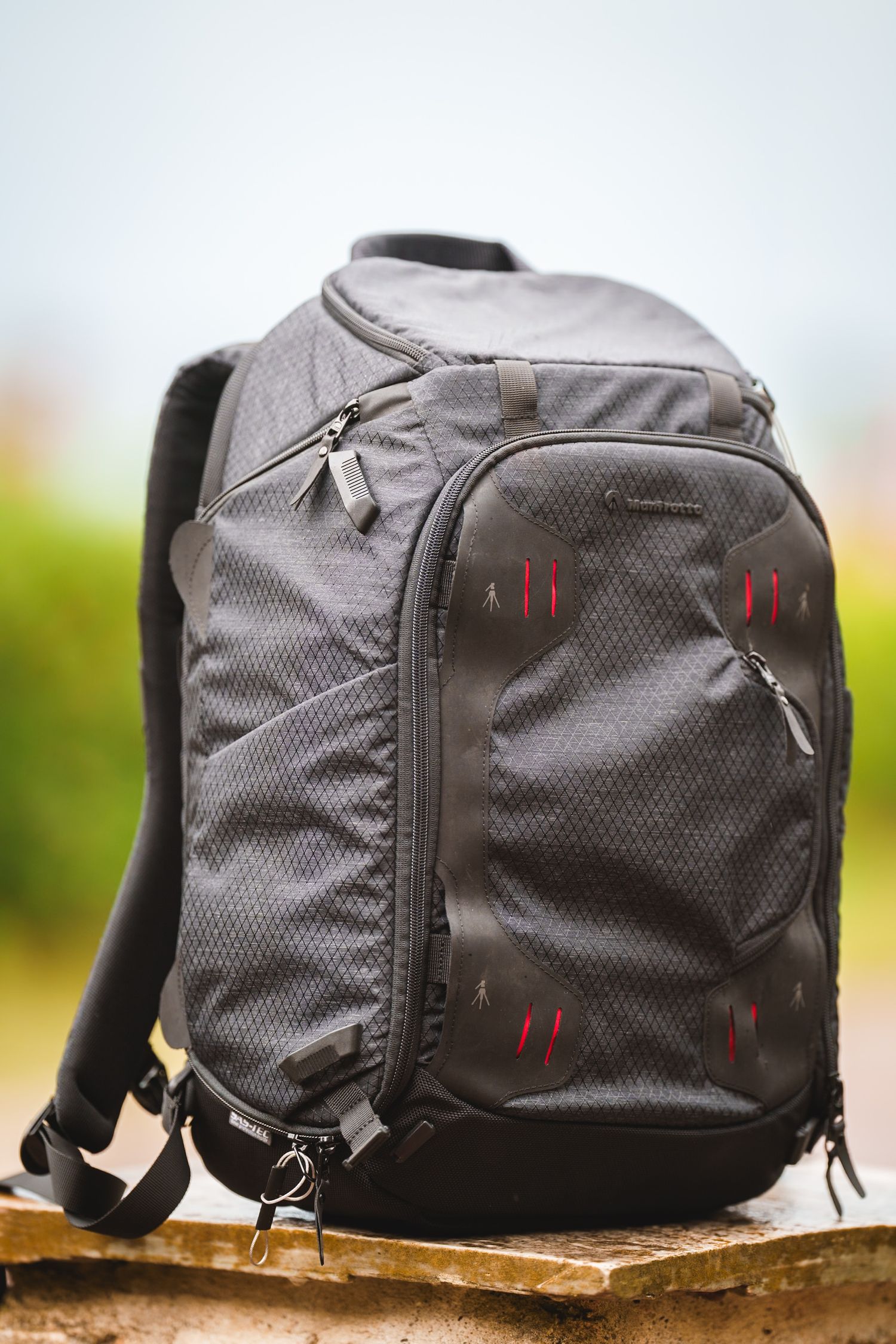 A sleek grey travel backpack shown from multiple angles with red accents and multiple compartments.