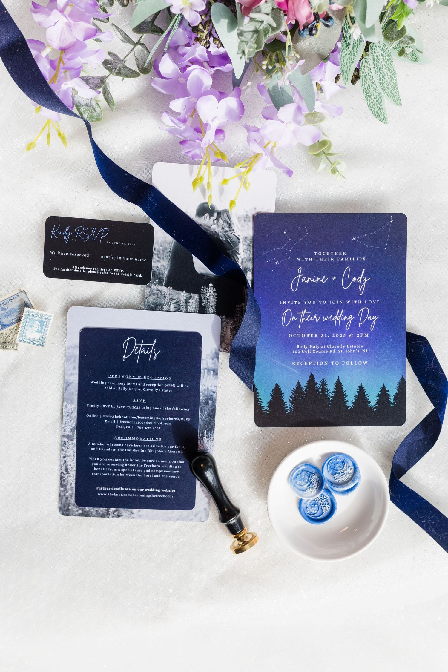 Navy blue wedding invitations with celestial design displayed with purple flowers and white ceramic dish on marble surface.