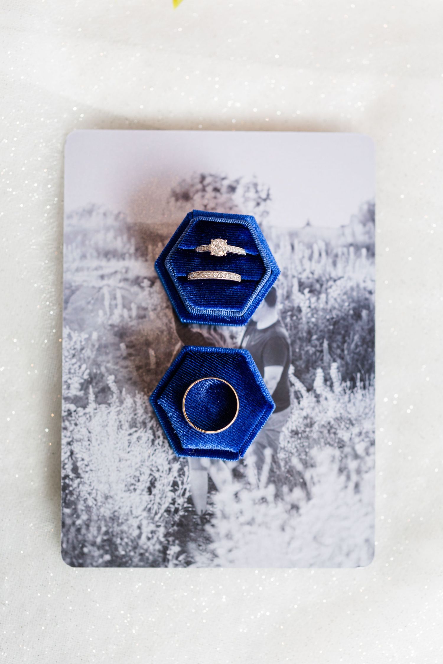 A royal blue velvet hexagonal ring box shown from three different angles on a white textured surface.