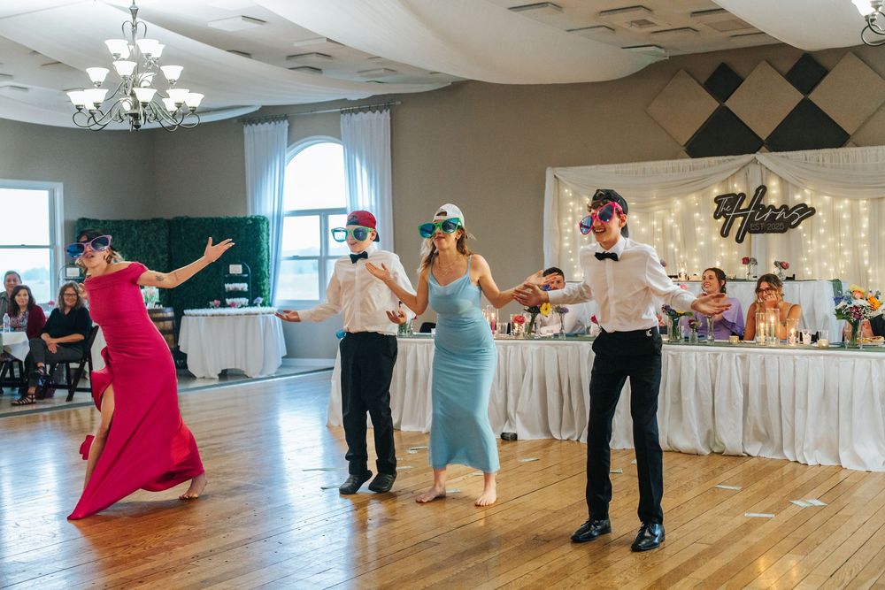 Couples dancing together in an elegant ballroom with white decor and chandeliers during a formal event.