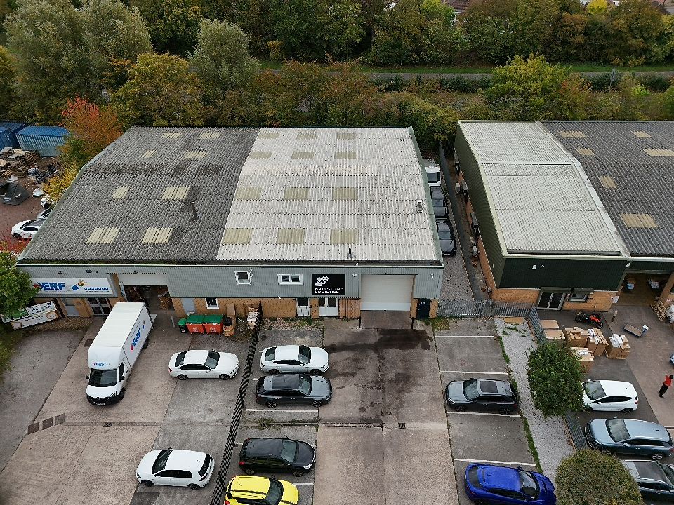 Aerial view of a parking lot with cars and buildings surrounded by autumn trees and foliage.