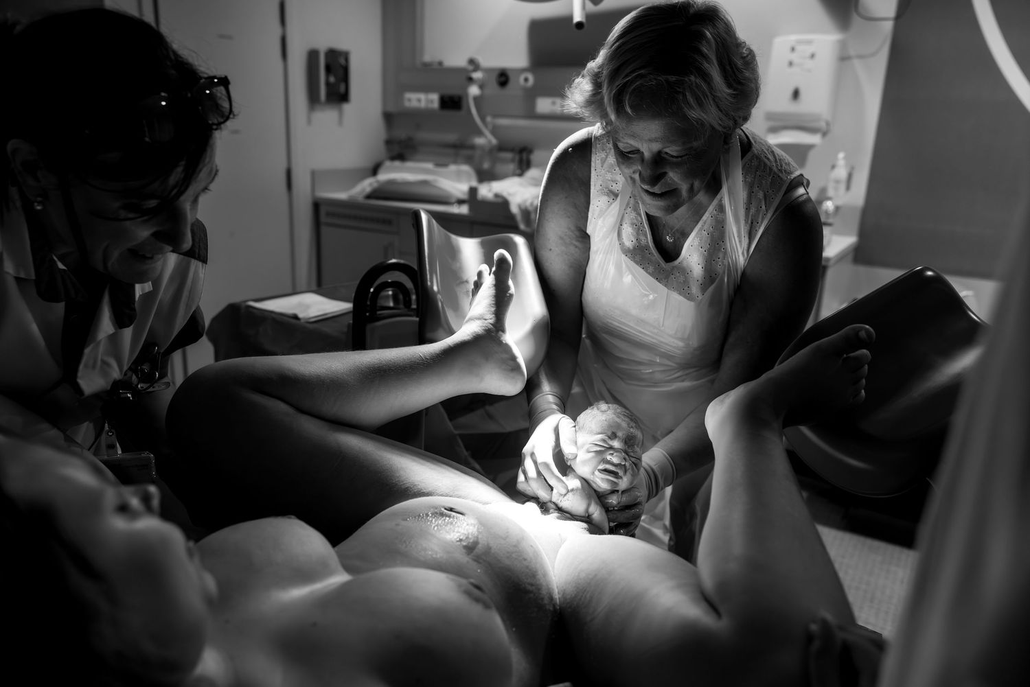 Black and white medical photography showing hands performing surgery in an operating room.
