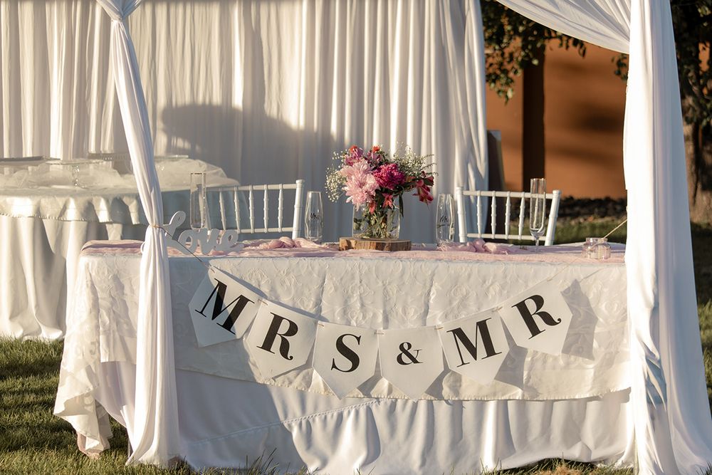 Decorated sweetheart table at outdoor Tri-Cities wedding reception with Mr. & Mrs. banner and floral arrangement