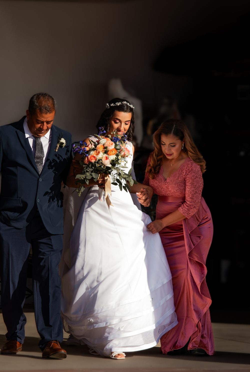 Bride entering ceremony with family escort, captured just before walking down the aisle