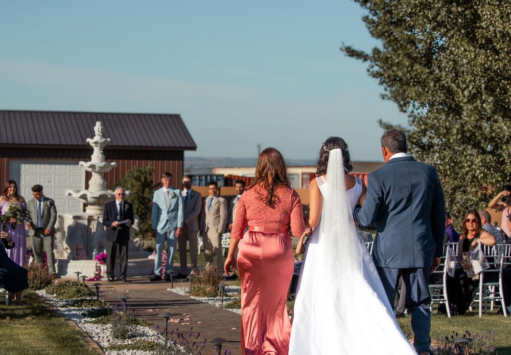 Bride being walked down the aisle by family while the groom waits at the altar during outdoor wedding in Tri-Cities WA