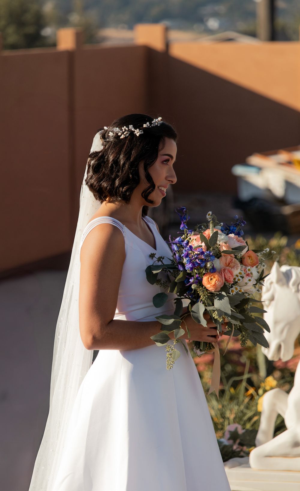 Bride in white dress holding bouquet of fall florals during golden hour bridal portraits