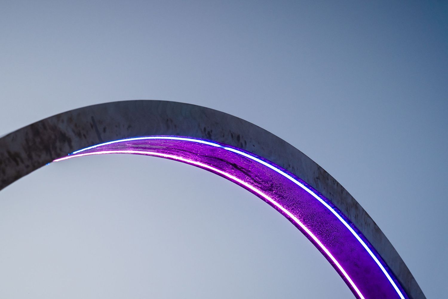 Curved architectural element with purple neon lighting against a dark background.