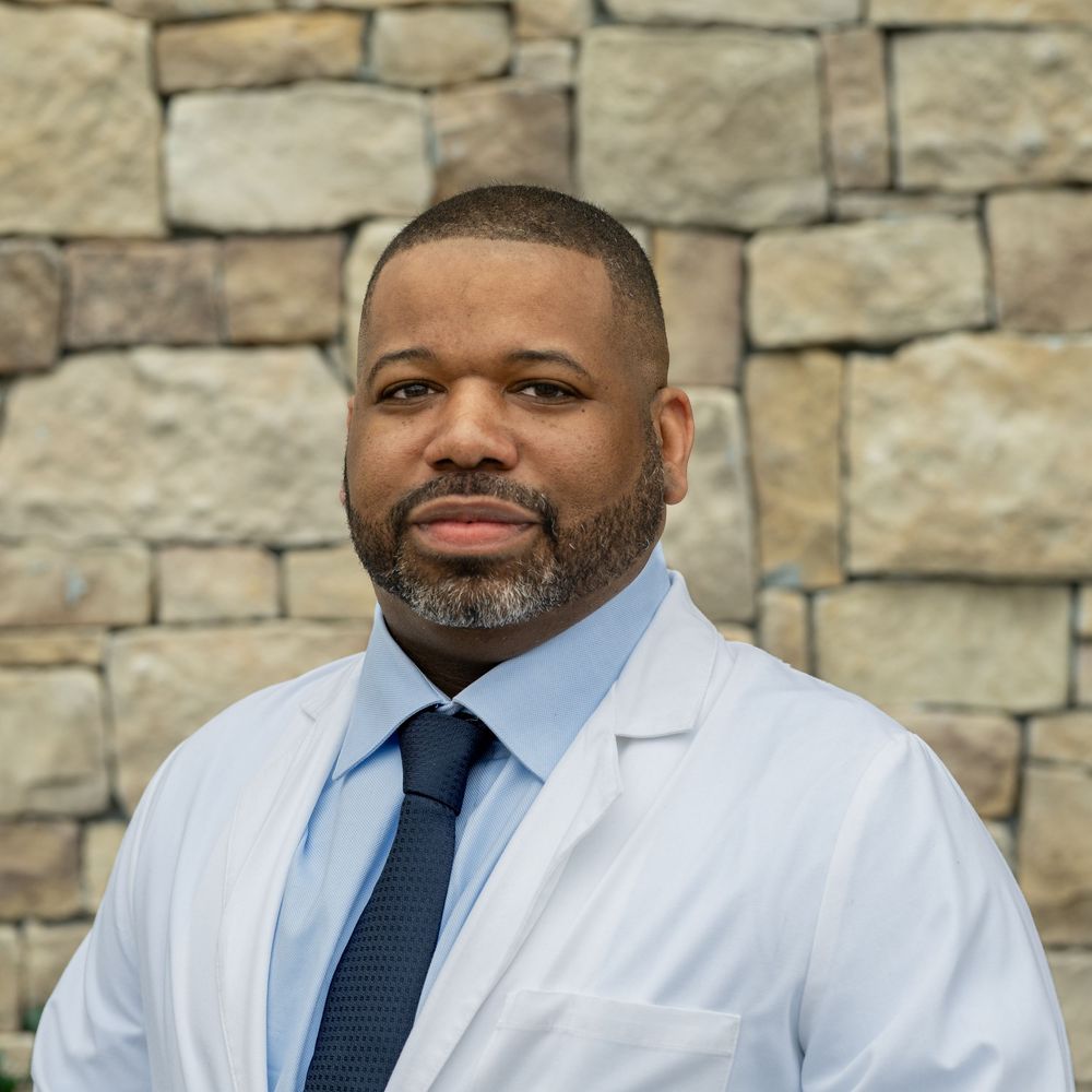 Professional medical portraits against a stone wall wearing white coats and ties.