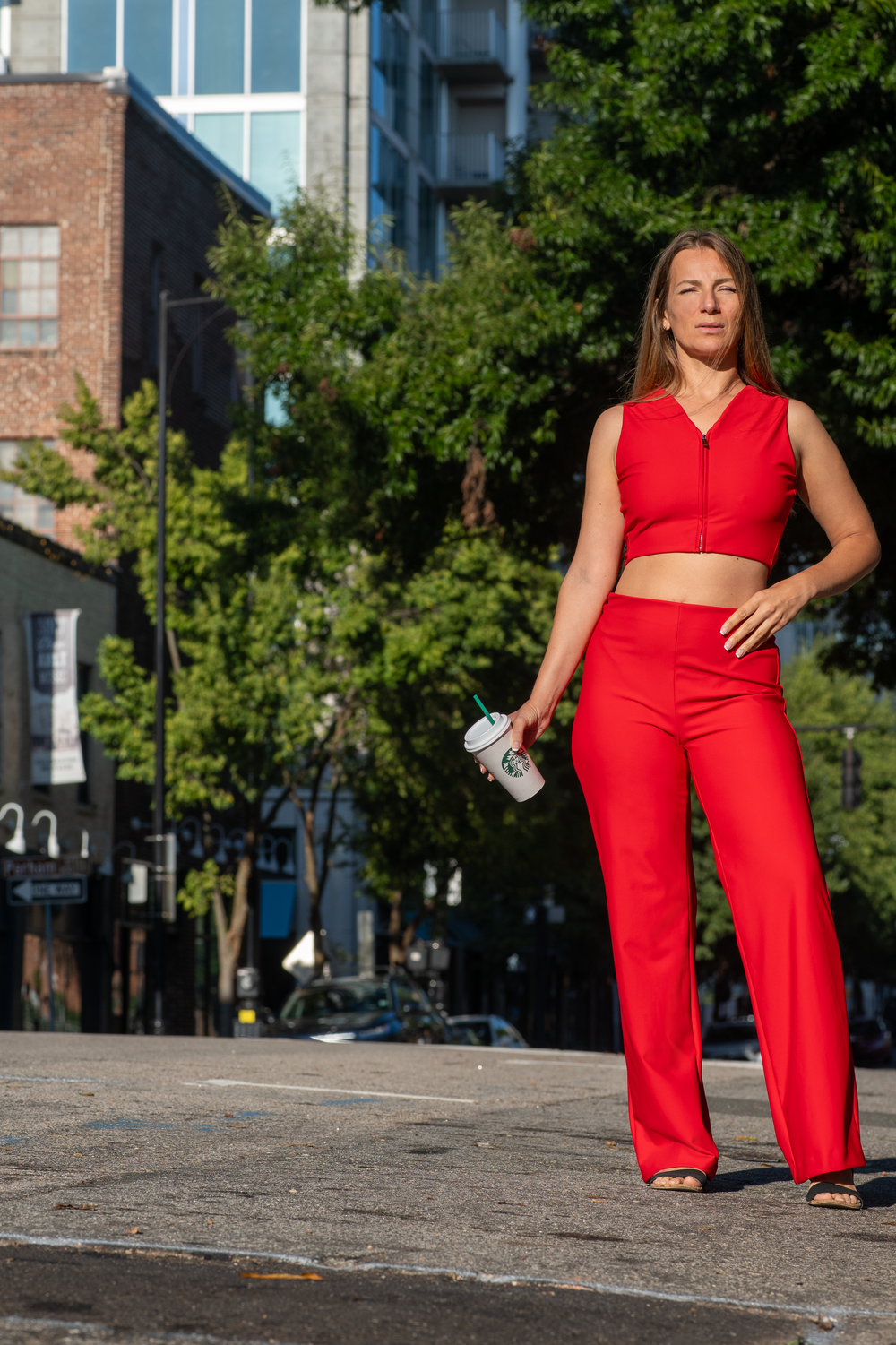 Bright red outfit ensemble photographed in an urban setting with buildings and trees.