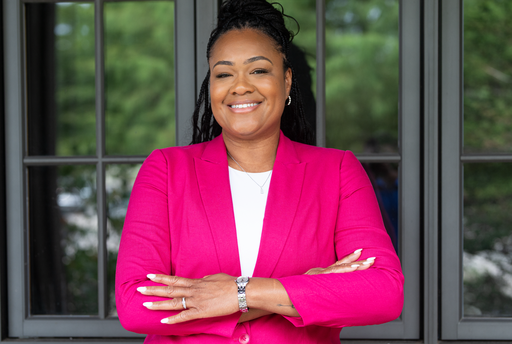 Professional portraits in bright pink blazer against dark window background.