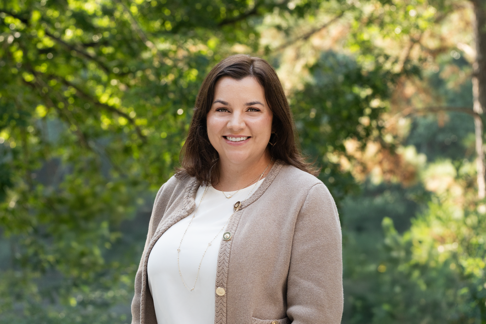 Professional portraits captured in an outdoor setting with lush green trees.