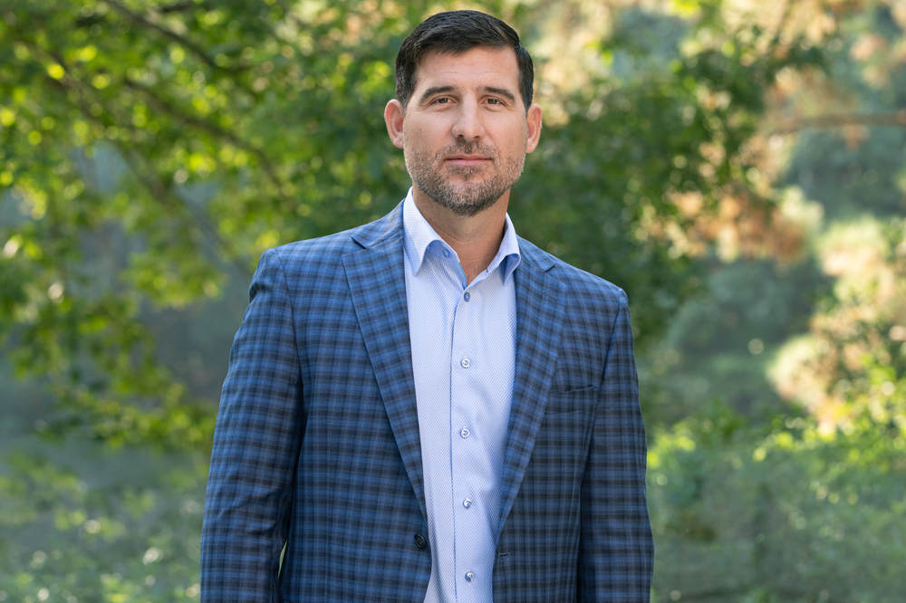 Business portraits taken outdoors with natural lighting and green foliage in background.