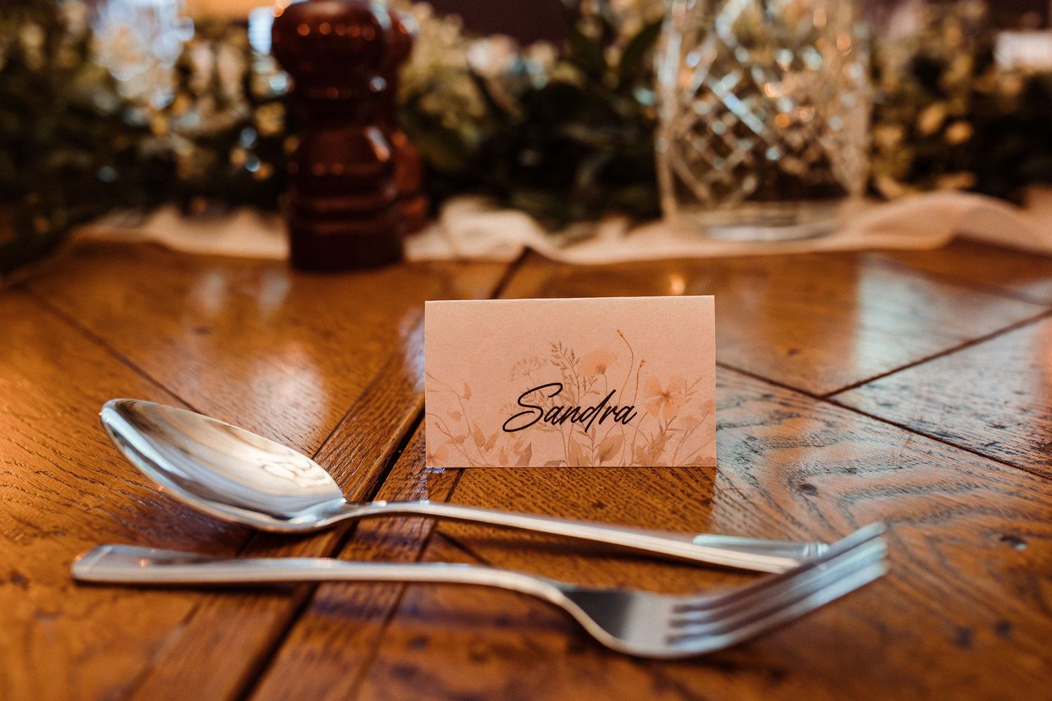 Place card and silverware setting on rustic wooden dining table.