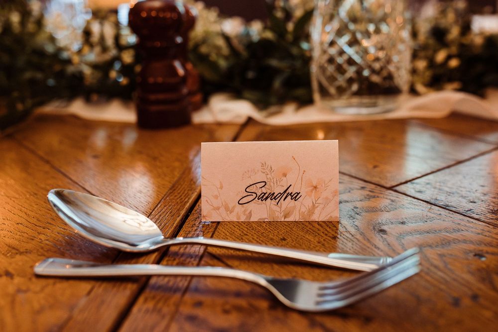 Place card and silverware setting on rustic wooden dining table.