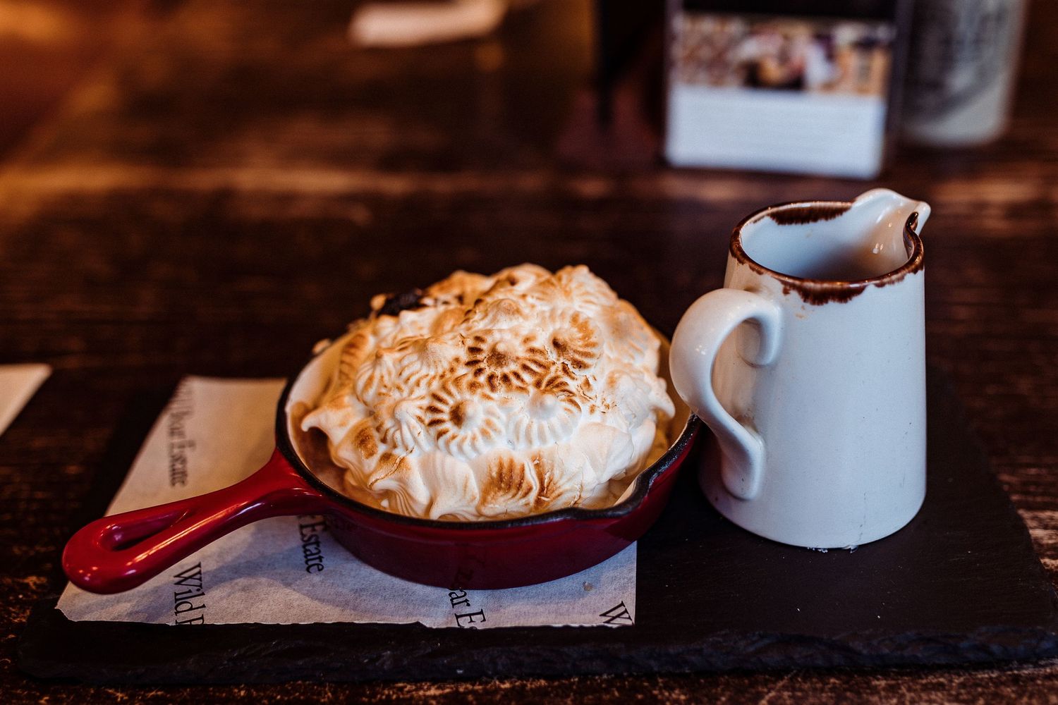 Homemade meringue dessert with whipped cream topping served on rustic wooden table.