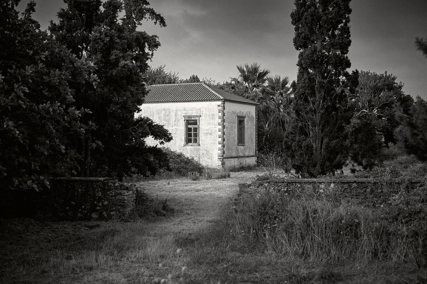 A series of black and white landscape photographs showing abandoned rural buildings and overgrown paths.