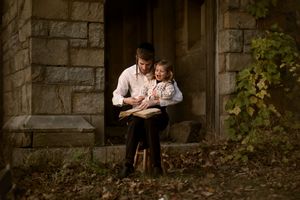 A tender family portrait session captured in a rustic stone setting with natural greenery and warm lighting.