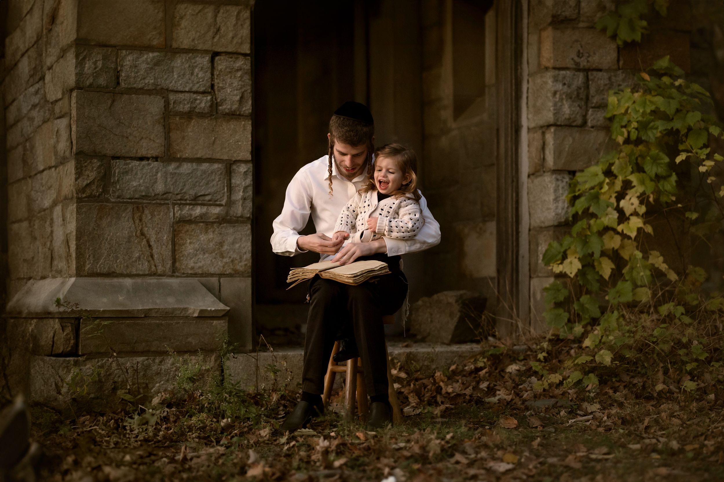 A tender family portrait session captured in a rustic stone setting with natural greenery and warm lighting.