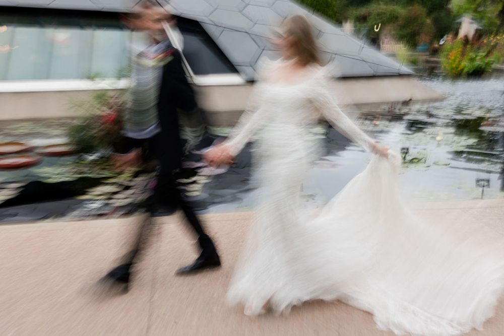 Motion blur of people walking through a modern office building corridor with glass walls and natural lighting.